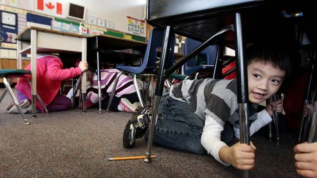 Grade 1 student Joseph Kim takes cover under his desk during an earthquake drill at Hollyburn Elementary School in West Vancouver, B.C., on Jan. 26, 2011. (Darryl Dyck/The Canadian Press)